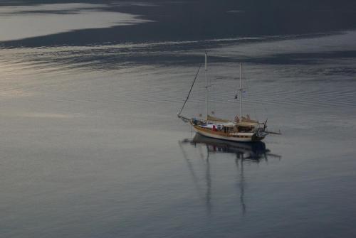 a boat in the water with its reflection in the water at Annas Studios in Livadia