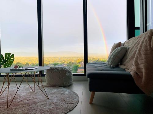 a living room with a couch and a table and large windows at Skygarden Luxury Condo in Glen Waverley
