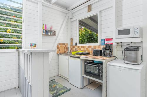 a white kitchen with a counter and a microwave at Appartement charmant au Carbet avec vue sur la mer - 50 m² in Le Carbet