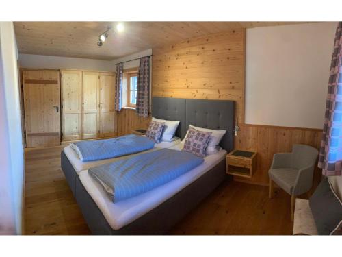 a bedroom with a bed with blue sheets and a chair at Webergütl - Chiemgau Karte in Inzell