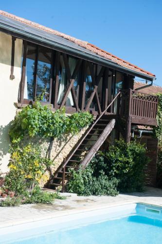 une maison avec un escalier en bois à côté d'une piscine dans l'établissement Au Moulié, à Blousson-Sérian