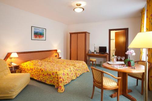 Pokój hotelowy z łóżkiem, stołem i krzesłem w obiekcie Logis Hotel-Restaurant De La Poste w mieście Urmatt
