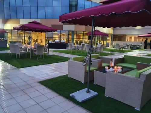 ein Restaurant mit Tischen, Stühlen und lila Sonnenschirmen in der Unterkunft PrideInn Plaza Nairobi Airport in Nairobi