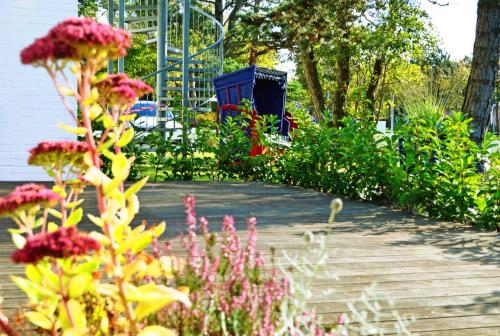 a garden with flowers and a playground in the background at Hotel Das kleine Glück - Adults Only in Sankt Peter-Ording