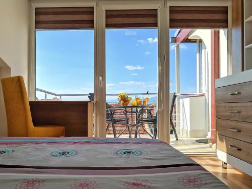 a bedroom with a bed and a balcony with a table at Sky Apartments in Strumica
