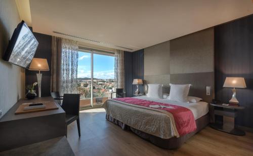 a hotel room with a bed and a desk and a window at Hotel MiM Sitges & Spa in Sitges