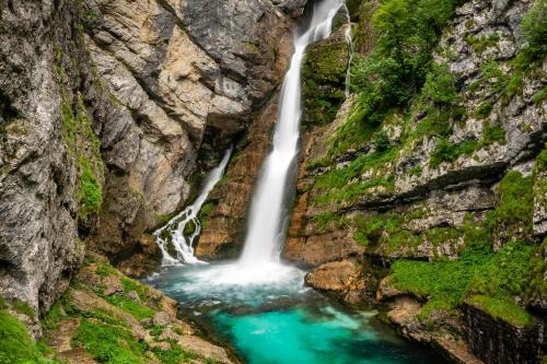 a waterfall in a canyon with turquoise water at PR`Cajhn in Radovljica
