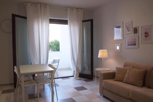 un soggiorno con divano, tavolo e finestra di Le Rose Beach & Suites appartamenti fronte mare a Villarosa a Martinsicuro