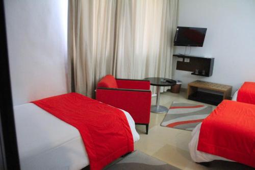 una habitación de hotel con 2 camas y una silla roja en hôtel LE PACHA, en Túnez