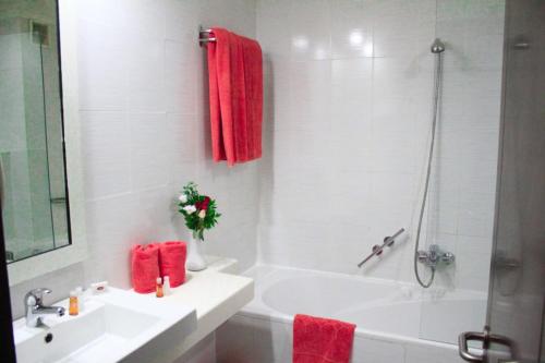 La salle de bains est pourvue d'un lavabo, d'une baignoire et de serviettes rouges. dans l'établissement hôtel LE PACHA, à Tunis