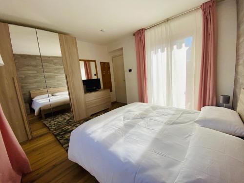 a bedroom with a large white bed and a mirror at Isabel in Pinzolo