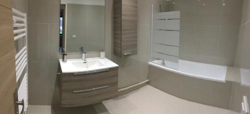 a white bathroom with a sink and a bath tub at Appart près de Meaux in Chambry