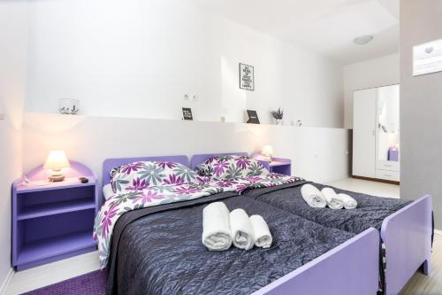 a bedroom with a purple bed with white shoes on it at Apartment Saulan in Dubrovnik