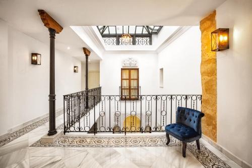 eine Treppe in einem Haus mit einem blauen Stuhl in der Unterkunft Hotel boutique Palacio de la Veracruz in Alcalá la Real