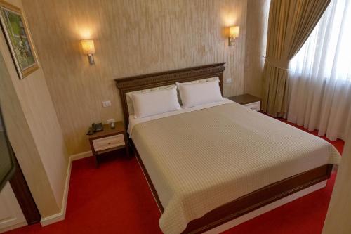a bedroom with a large bed and a red carpet at Rozafa Hotel in Shkodër