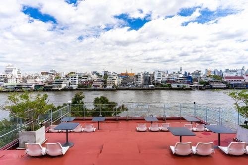 une terrasse avec des chaises et des tables, ainsi qu'une rivière dans l'établissement Amdaeng Bangkok Riverside Hotel - SHA Plus Certified, à Bangkok