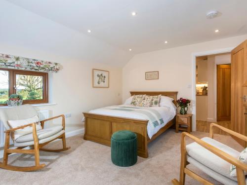 a bedroom with a bed and two chairs and a window at Bay Tree Cottage in Droitwich