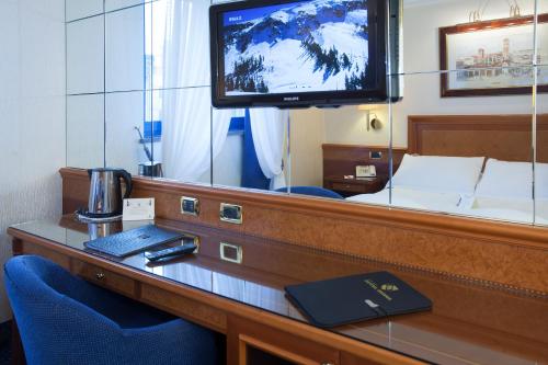 a room with a desk with a tv and a bed at Hotel Berna in Milan