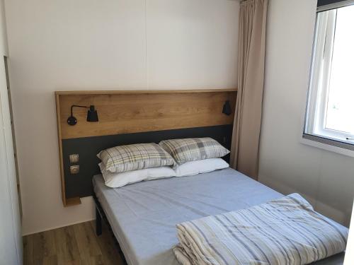 un petit lit avec deux oreillers dans une chambre dans l'établissement Mobile Homes by KelAir at Camping La Yole, à Saint-Jean-de-Monts