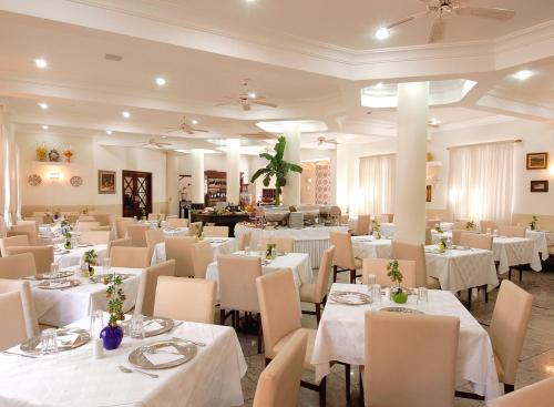 a dining room with white tables and white chairs at Hotel Da Vinci in Serra Negra