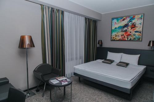 a hotel room with a bed and a chair at Mercure Kyiv Congress in Kyiv