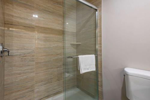 a glass shower door in a bathroom with a toilet at The Waves Hotel, Ascend Hotel Collection in Wildwood