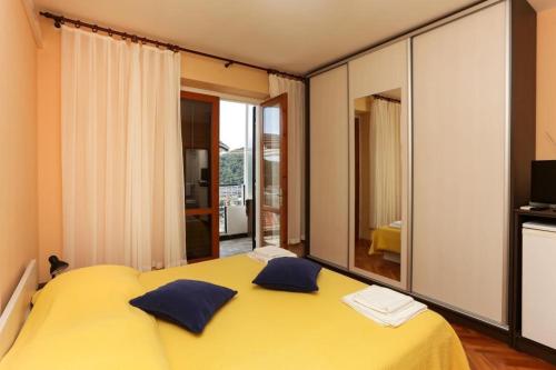 a yellow bed with blue pillows in a bedroom at Lapad View Apartments in Dubrovnik