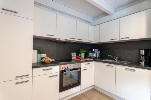 a white kitchen with white cabinets and appliances at Weberhof Ferienapartments in Rostrup am Westufer des Zwischenahner Meers in Bad Zwischenahn