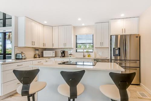 a large kitchen with white cabinets and black chairs at Orient Expressed in Longboat Key