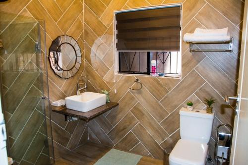 a bathroom with a toilet and a sink and a mirror at Mrhali Boutique Guest House in Kwamhlanga