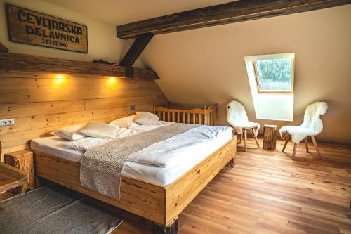 a bedroom with a bed and two white chairs at Tourist Farm Šenkova Domačija in Zgornje Jezersko