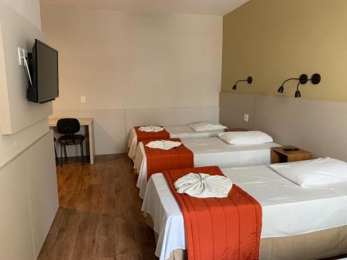 um quarto com 4 camas e uma televisão de ecrã plano em Hotel Cisne em São Paulo