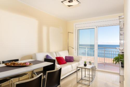 a living room with a white couch and a view of the ocean at Hauzify I Apartament Cannes in Platja d'Aro