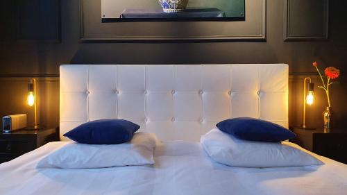 ein weißes Bett mit zwei blauen Kissen darauf in der Unterkunft Residenz Stadslogement in Den Haag