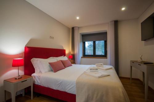 a bedroom with a large bed with a red headboard at Quinta Vilar e Almarde in Castelo de Paiva