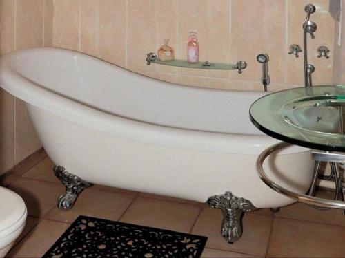 a white bath tub in a bathroom with a sink at Tamarisk Guest Lodge in Benoni