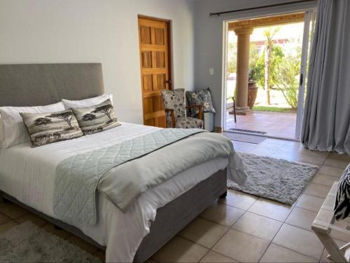 een slaapkamer met een groot bed en een glazen schuifdeur bij Tamarisk Guest Lodge in Benoni