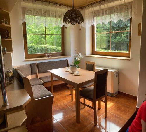- une salle à manger avec une table, des chaises et 2 fenêtres dans l'établissement Apartmá Doubek, à Rokytnice nad Jizerou