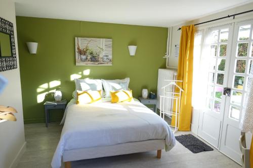 a bedroom with green walls and a bed with yellow pillows at Chambres d'hôtes Les Magnolias in Saint-Chéron