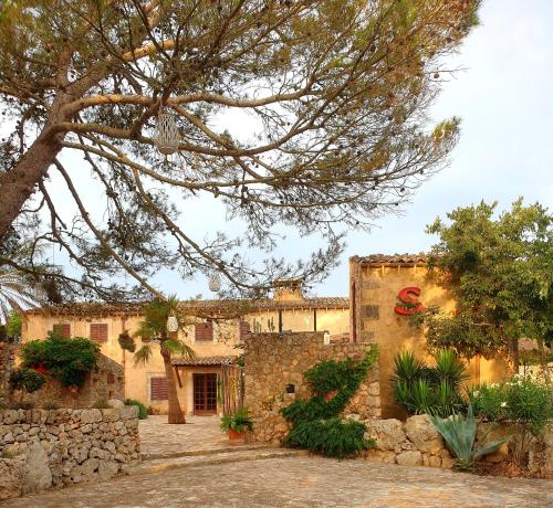 un bâtiment en pierre avec un arbre en face dans l'établissement Las Fincas de Annie, à Felanitx