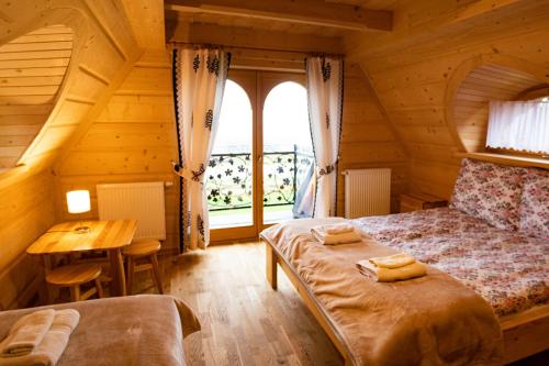 a bedroom with a bed and a table and a window at Domki Pod Tatrami in Rzepiska