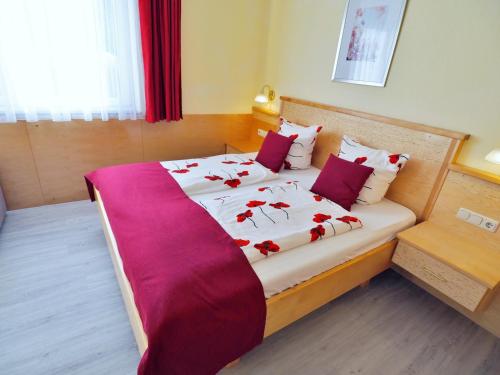 a bedroom with a bed with red flowers on it at Pension Kathi in Sankt Kanzian