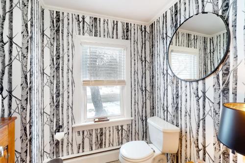 a bathroom with black and white wallpaper with a toilet and a mirror at Casa Okemo in Ludlow