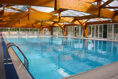 een groot zwembad met blauw water in een gebouw bij Azureva Cap d'Agde in Cap d'Agde