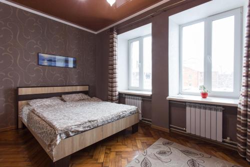 a bedroom with a bed and two windows at Апартаменты на Лермонтовской in Kharkiv