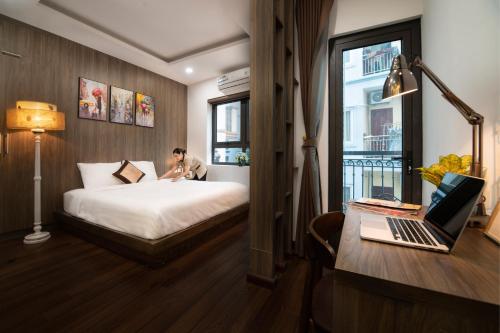 Bao Hung Hotel & Apartment - Tran Thai Tong في هانوي: رجل يجلس على سرير في غرفة فندق