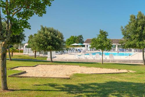 a sandbox in a park with a pool and trees at Azureva Fouras in Fouras