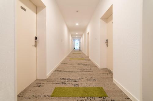 an empty corridor with white walls and green rugs at Hotel zum Kuhhirten in Bremen