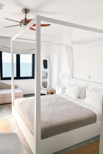 a white bedroom with a white canopy bed with a ceiling at Samothraki Beach Boutique Hotel in Makrilies