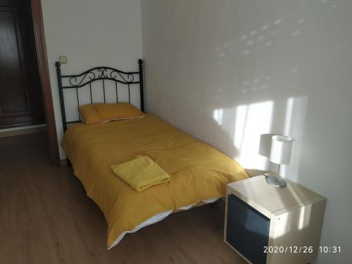 Cette chambre comprend un lit avec une couverture jaune et une télévision. dans l'établissement Apartamento TISARE wifi, à Valladolid